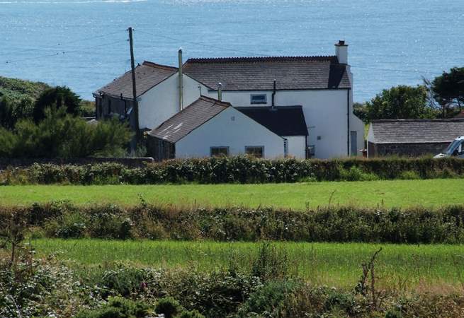 Stargazy Skies is the single-storey cottage in the middle of the picture with two windows. The backdrop of the sea is stunning.