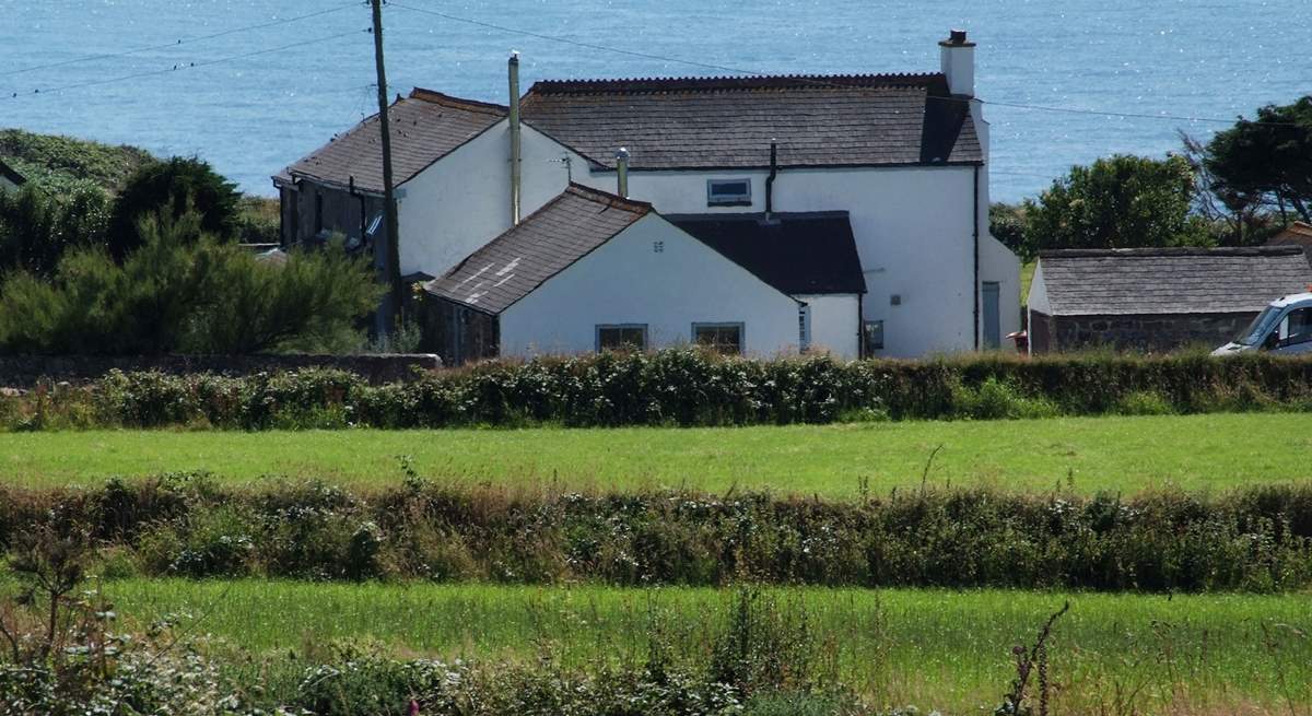 Stargazy Skies is the single-storey cottage in the middle of the picture with two windows. The backdrop of the sea is stunning.