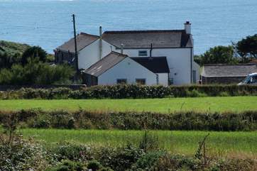 Stargazy Skies is the single-storey cottage in the middle of the picture with two windows. The backdrop of the sea is stunning.