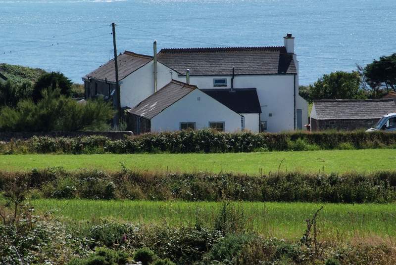Stargazy Skies is the single-storey cottage in the middle of the picture with two windows. The backdrop of the sea is stunning.