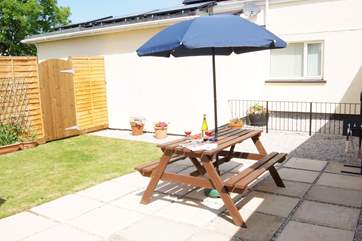 The patio-area and garden bask in sunshine, ideal for a barbecue.