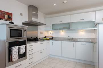 The contemporary kitchen has plenty of storage and there is a very useful separate utility room off it.