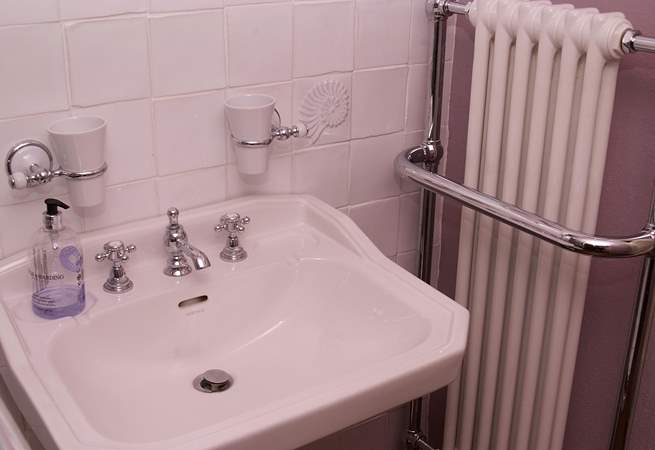 The bathroom in the cottage is gorgeously fitted out with a sink, bath and a stylish radiator.