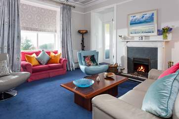 The sitting-room with stylish and comfy sofas around the fire.