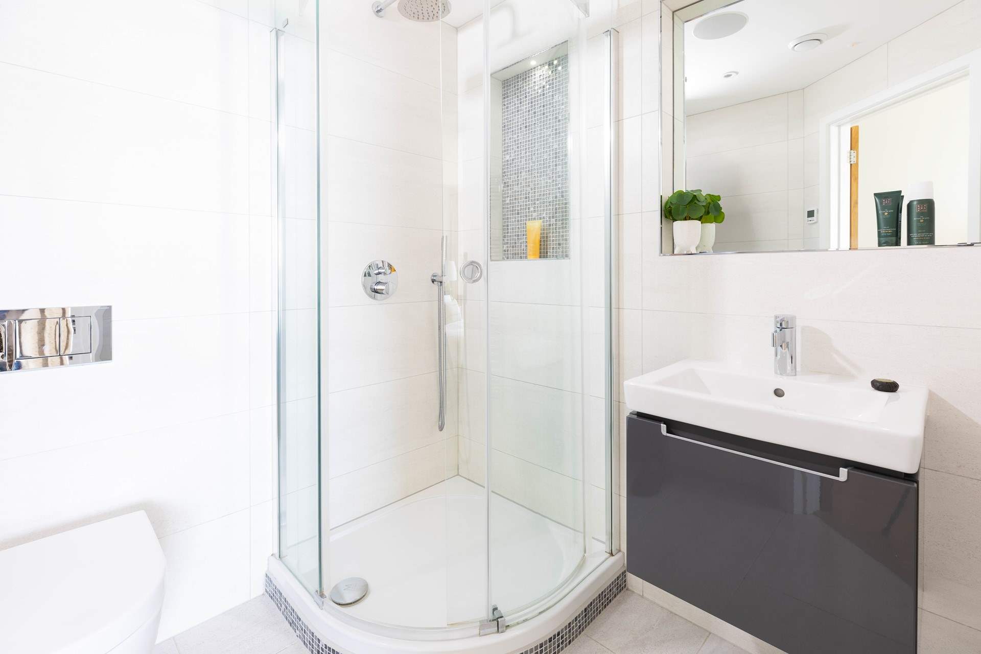 The en suite is sleek and contemporary, complete with power shower and modern lighting.