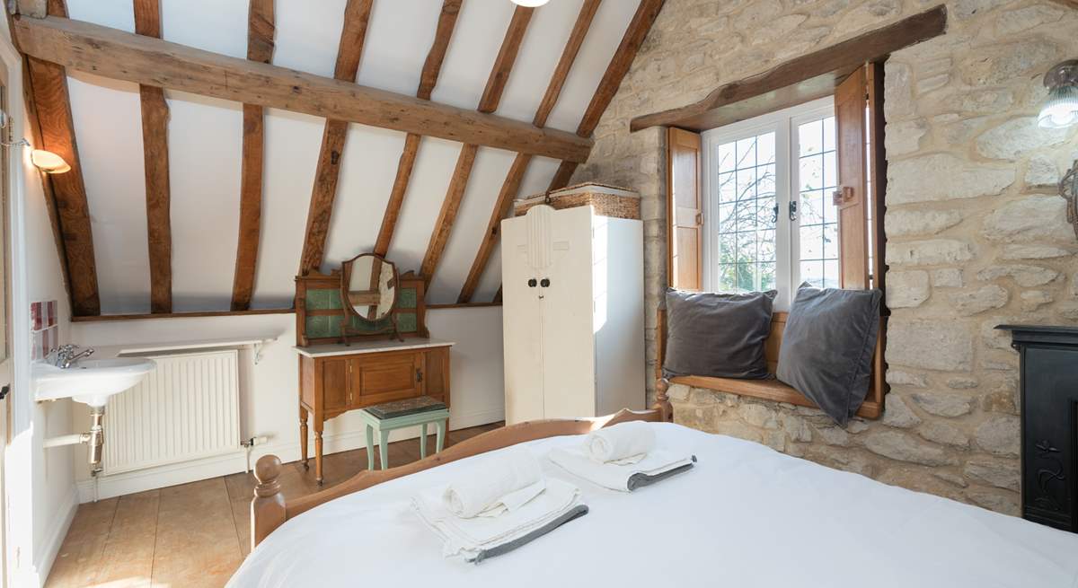 The bedroom has lovely exposed stone walls and a tall beamed ceiling.