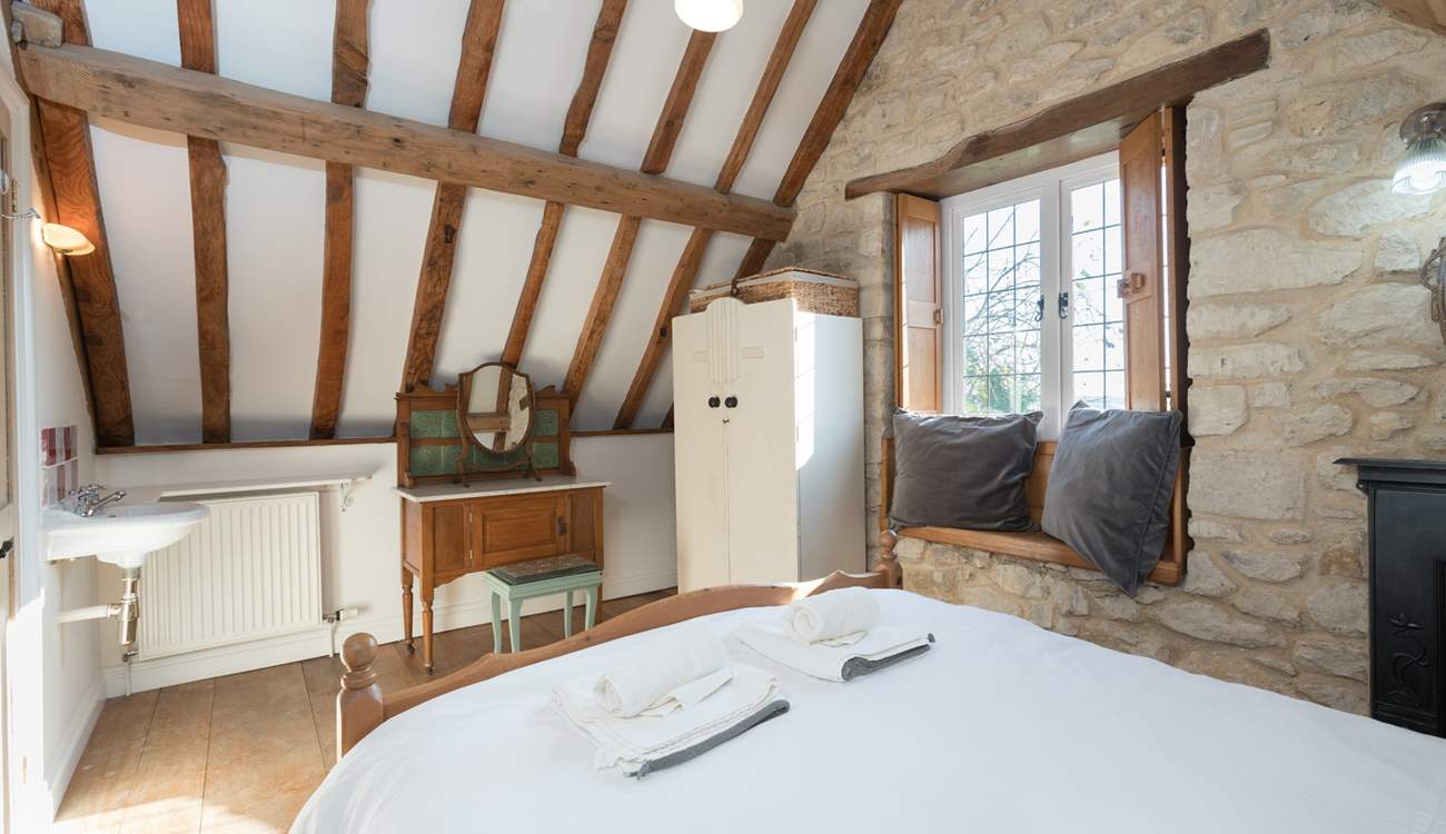 The bedroom has lovely exposed stone walls and a tall beamed ceiling.