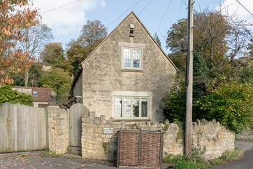 This is another view of the front of the cottage, the patio is tucked between the stone wall and the cottage, and a path leads down the side to the front door.