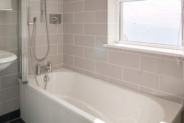 The bathroom is well designed with soft grey tiles and slate floor.