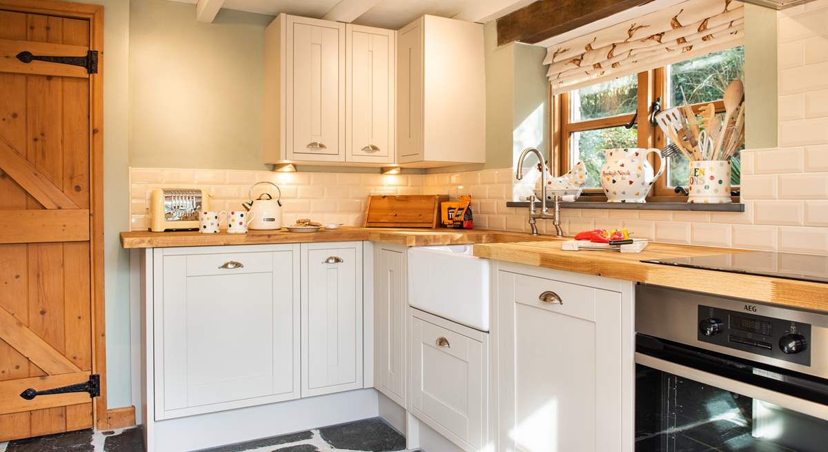 The slate floor, wooden work surface and pretty country themed fabric perfectly complement the cottage.