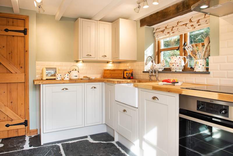 The slate floor, wooden work surface and pretty country themed fabric perfectly complement the cottage.