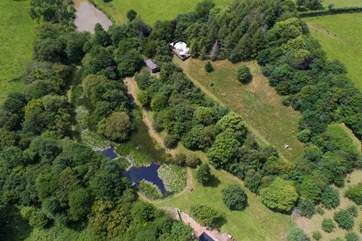 An aerial view of Ashley's Shack tucked into the woodland overlooking the pond. Here you can also see Poppy Yurt, they are both private from each other with plenty of space for all.