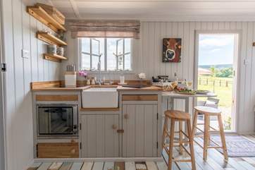 The kitchen window looks out over the patio and farmland beyond. There is a two-ring hob and mini oven and a gas fridge.