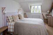 The main bedroom has a generous king-size double bed (5') with gorgeous linens and an en suite bathroom.