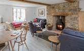 The open plan sitting/dining-room has three sofas to choose from and a cosy wood-burner. - Thumbnail Image