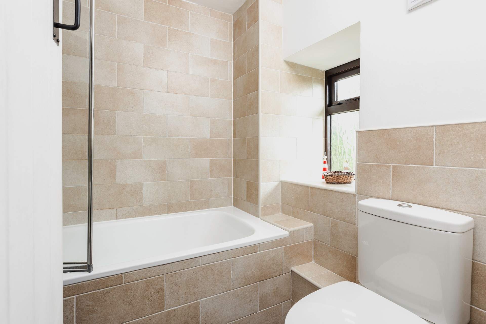 The bathroom has a bath with shower over.