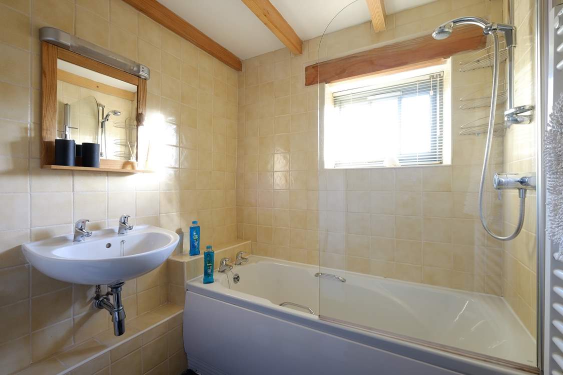 The bathroom has a bath with shower over.