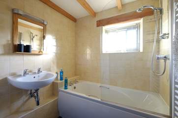 The bathroom has a bath with shower over.