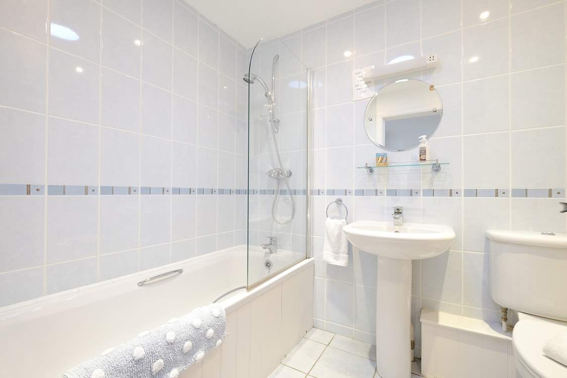 The bathroom has a bath with shower over.