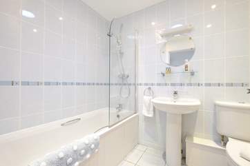 The bathroom has a bath with shower over.