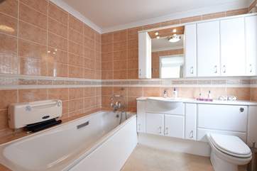 The spacious bathroom has a bath with shower over.