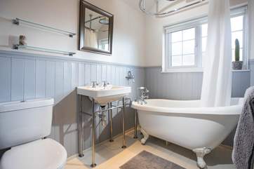 A bathroom that offers a wonderful waterfall shower and roll top bath.