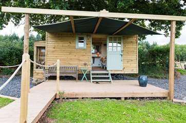Not only is this delightful hut sheltered by the oak tree, the owner has even installed a sail shelter for extra outdoor living space.