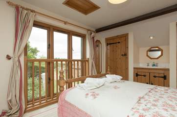 The master bedroom is on the mezzanine level with views out to the front of the cottage and a little secret window over the living room.