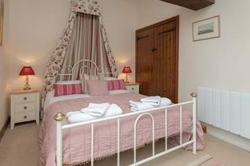 This is the master bedroom. The bed offers a touch of luxury to the feel of the room, which overlooks the large enclosed garden