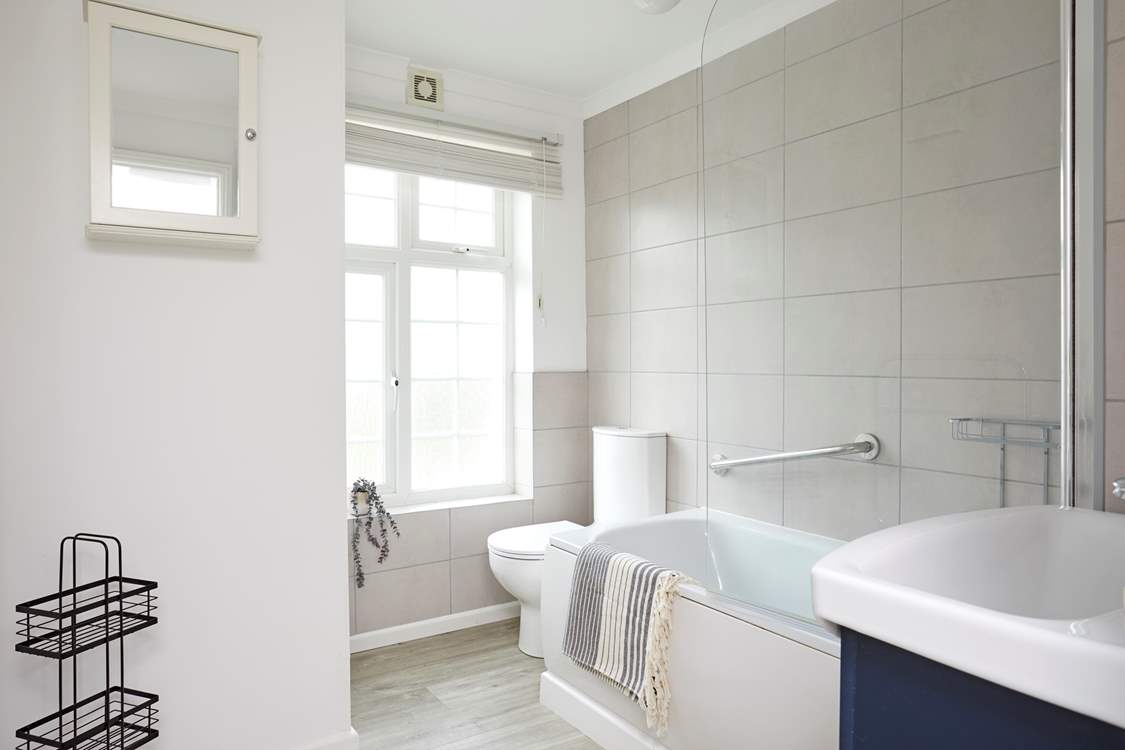 The modern bathroom features a shower over a bathtub.