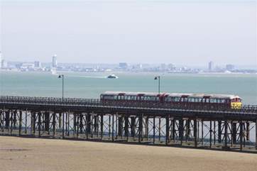 Watch the island train trundle its way up the Victorian pier to collect and drop off passengers for the catamaran.