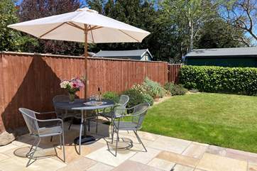 A charming enclosed garden with patio furniture and sun loungers