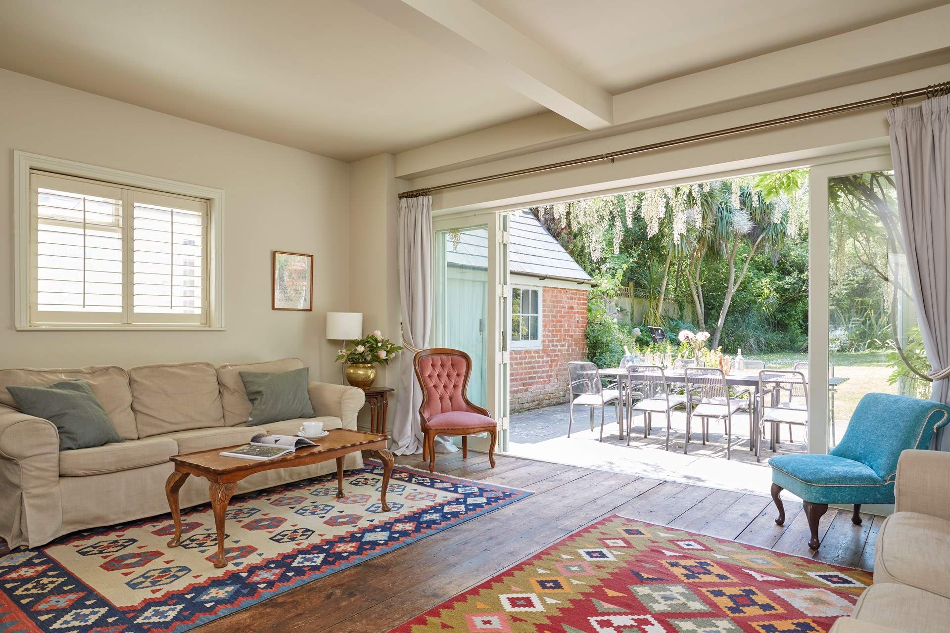 The sitting-room with wooden floors and kilim area rugs. Enjoy the inviting view of the garden.