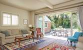 The sitting-room with wooden floors and kilim area rugs. Enjoy the inviting view of the garden. - Thumbnail Image