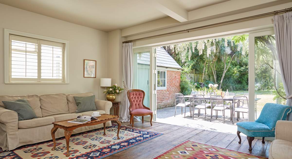 The sitting-room with wooden floors and kilim area rugs. Enjoy the inviting view of the garden.