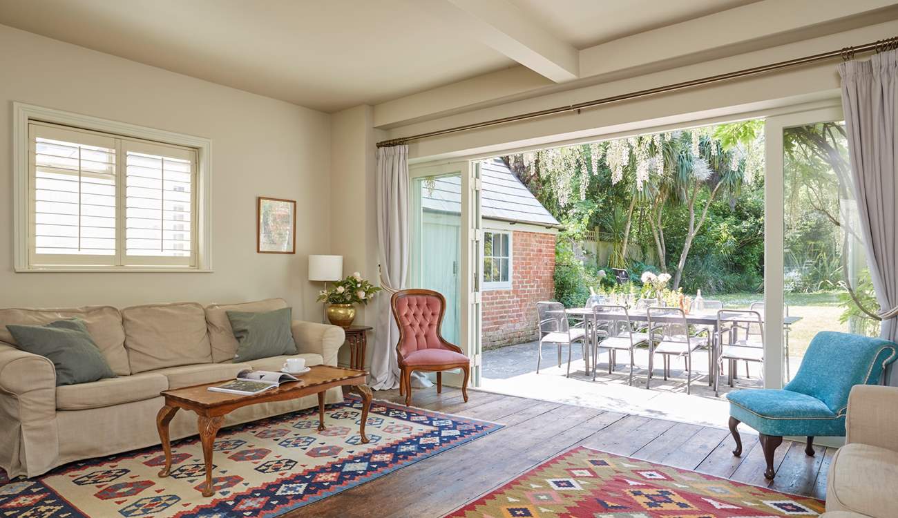 The sitting-room with wooden floors and kilim area rugs. Enjoy the inviting view of the garden.