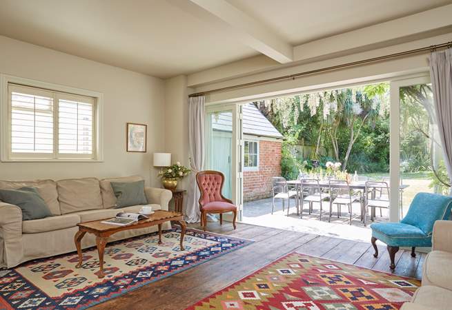 The sitting-room with wooden floors and kilim area rugs. Enjoy the inviting view of the garden.