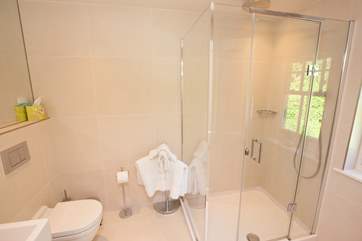 The en suite off the second double bedroom with spacious shower and a light and modern decor.