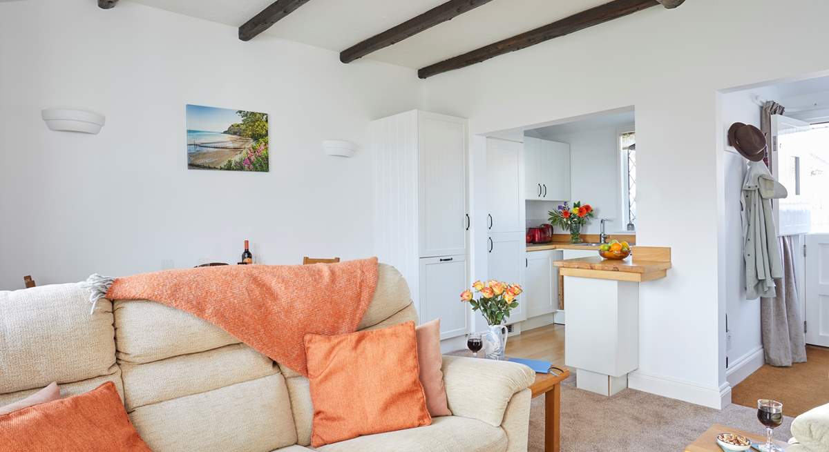 The open plan living room area with comfortable seating looking towards the kitchen and entrance.  