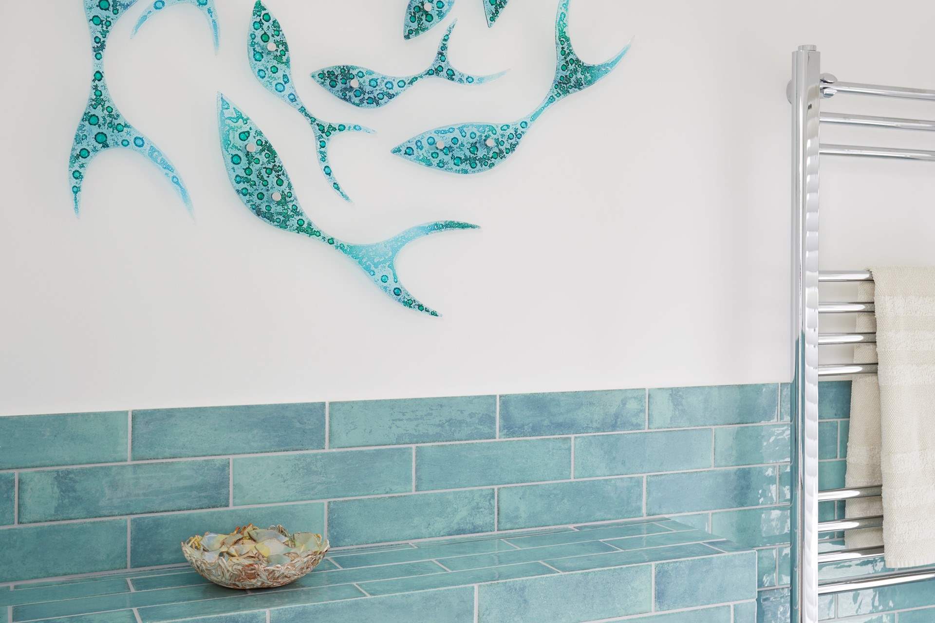 Glass, fish art detailing on the bathroom wall.