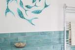 Glass, fish art detailing on the bathroom wall.
