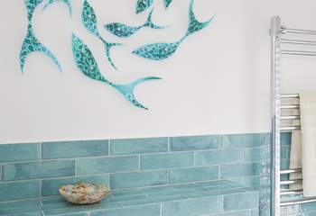 Glass, fish art detailing on the bathroom wall.