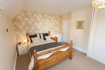 The main bedroom has gently sloping ceilings and is comfortably furnished.