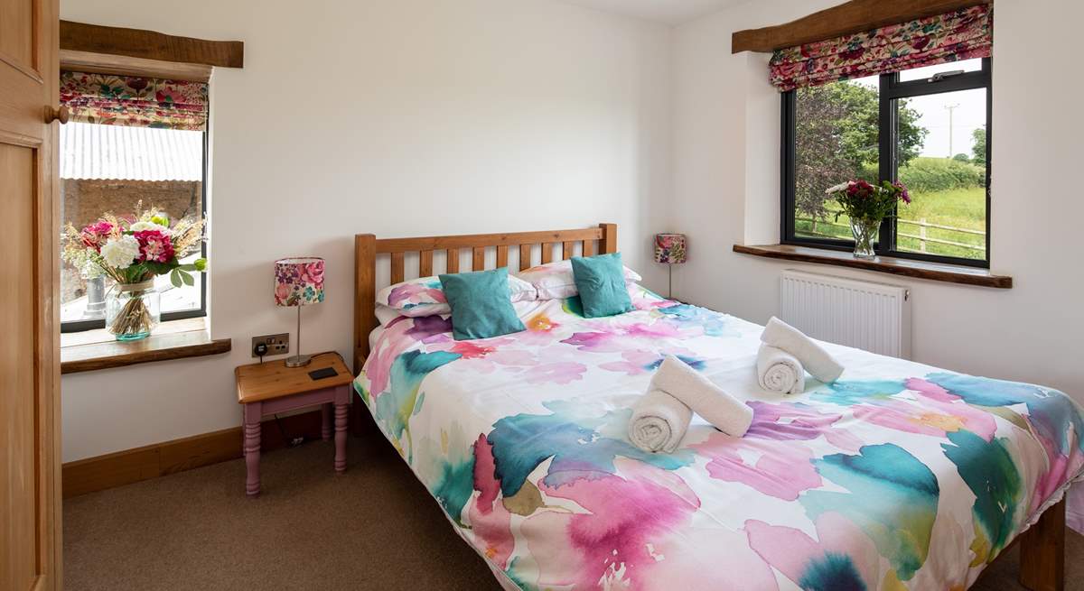 Bedroom two has a king-size bed and views out over the fields and a glimpse of the oldest part of the farmstead at the side.