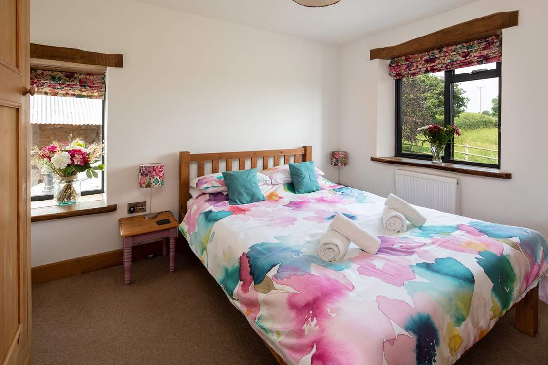 Bedroom two has a king-size bed and views out over the fields and a glimpse of the oldest part of the farmstead at the side.