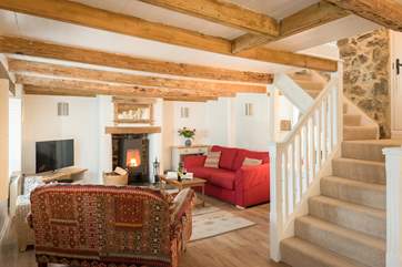 The comfortable sitting-area around the contemporary wood-burner with original beamed ceiling, if you are over 6ft tall you may need to duck and mind your head on the way up the stairs!