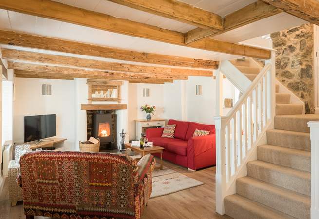 The comfortable sitting-area around the contemporary wood-burner with original beamed ceiling, if you are over 6ft tall you may need to duck and mind your head on the way up the stairs!