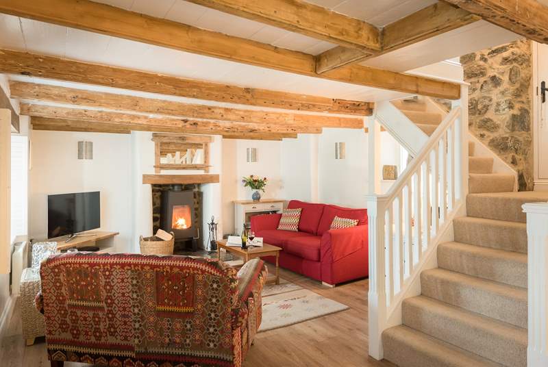 The comfortable sitting-area around the contemporary wood-burner with original beamed ceiling, if you are over 6ft tall you may need to duck and mind your head on the way up the stairs!