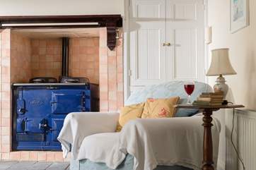 A comfy chair by the feature Rayburn (not working purely for decoration) and a toy and games cupboard in the corner.