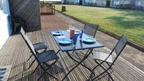 Enjoy breakfast on the decking with views across the communal lawn towards the sea.